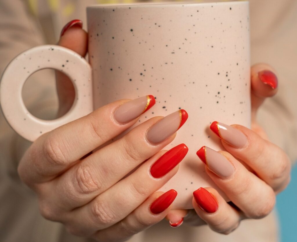 Mãos segurando uma xícara com unhas pintadas de de vermelha e francesinha