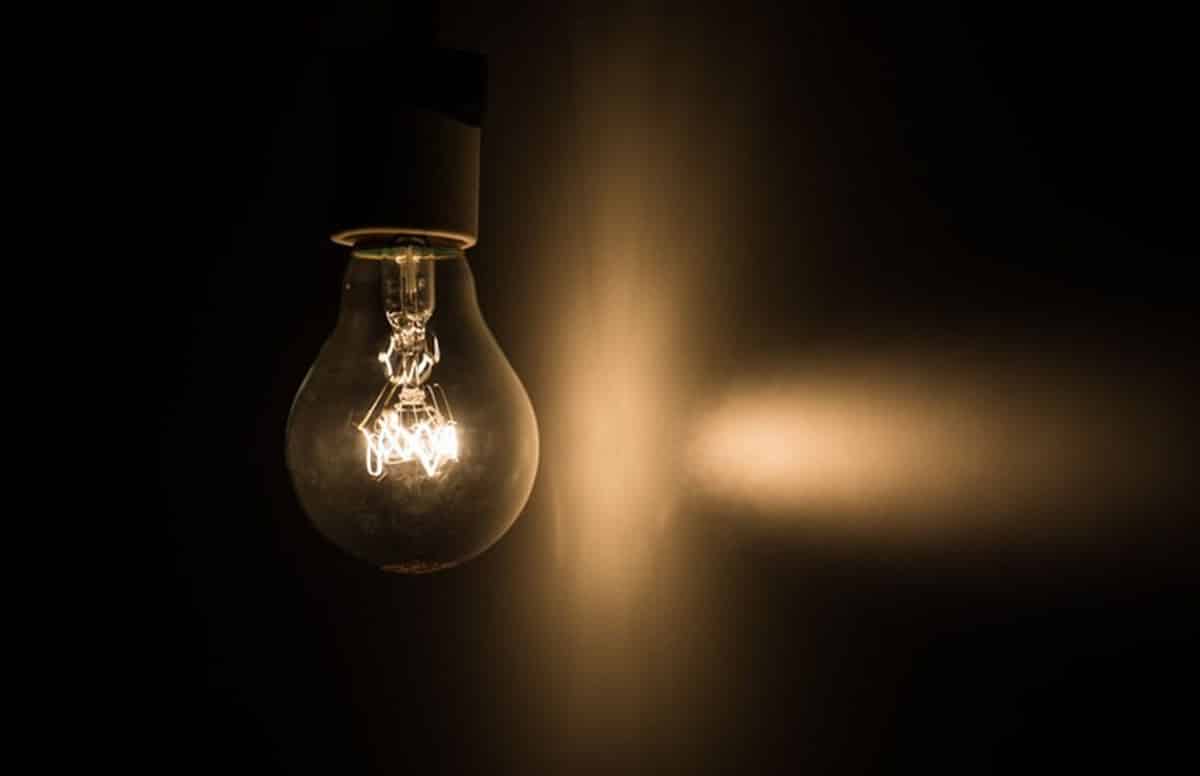 Lâmpada acesa num ambiente escuro fazendo relação com a Tarifa Social de Energia