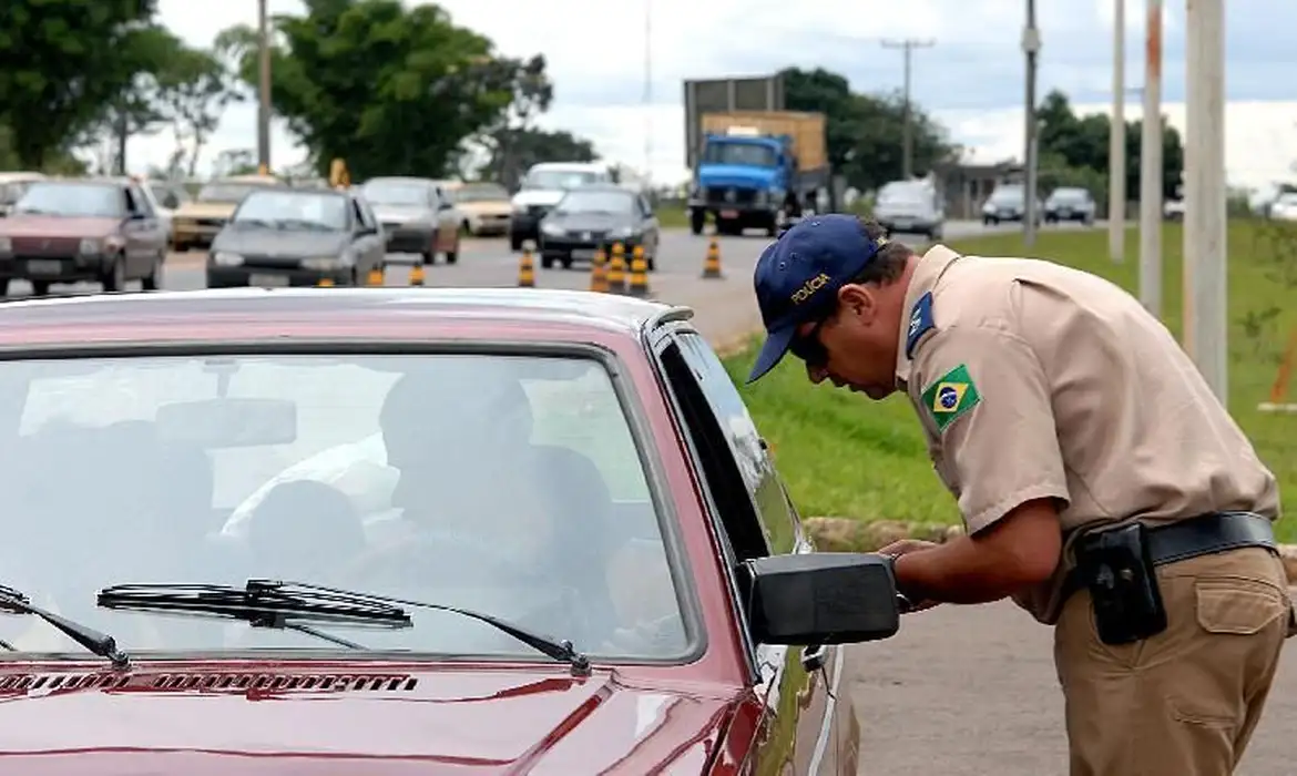 Imagem de um policial aplicando uma multa no motorista