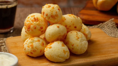 Deliciosos pães de queijo mineiros crocantes por fora e macios por dentro, servidos sobre uma tábua de madeira.