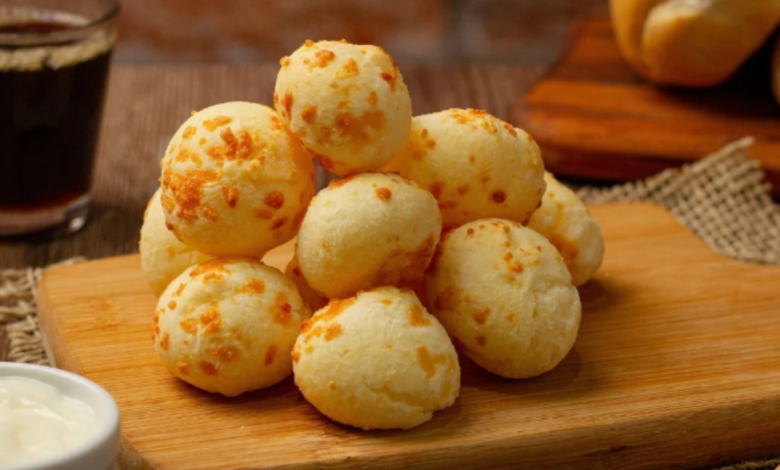 Deliciosos pães de queijo mineiros crocantes por fora e macios por dentro, servidos sobre uma tábua de madeira.