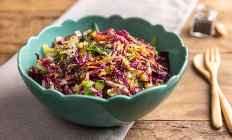 Salada crocante e colorida em tigela verde, feita com repolho roxo, cenoura, pepino e molho cremoso, servida sobre mesa rústica.