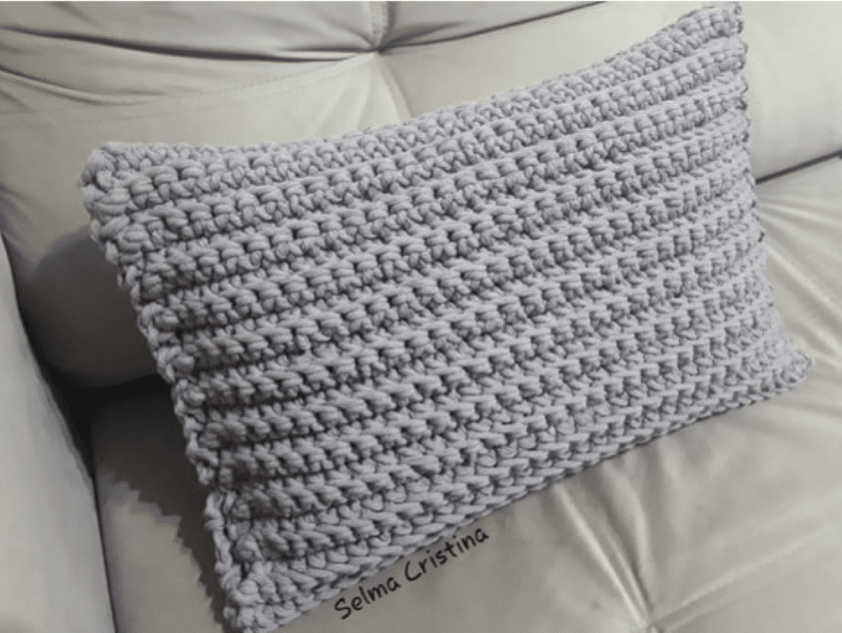 Almofada de crochê com ponto puff, tecida com fio grosso na cor cinza claro, perfeita para decorar sua sala com conforto.