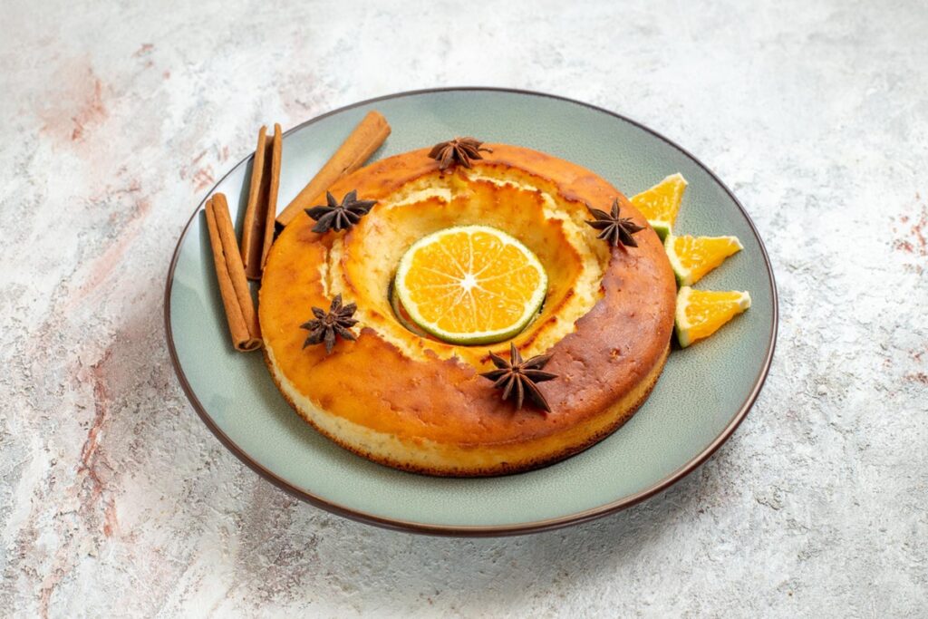 Bolo de laranja decorado com estrelas de anis e fatias de laranja, servindo como um toque especial para a sobremesa.