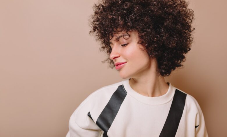 Mulher de cabelo curto e cacheado, com um visual moderno e estiloso para o verão.