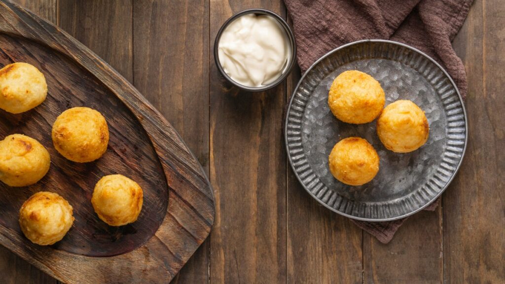 Pãozinhos de tapioca frescos acompanhados de um pote de requeijão, representando a receita fácil e deliciosa de pãozinho de tapioca.