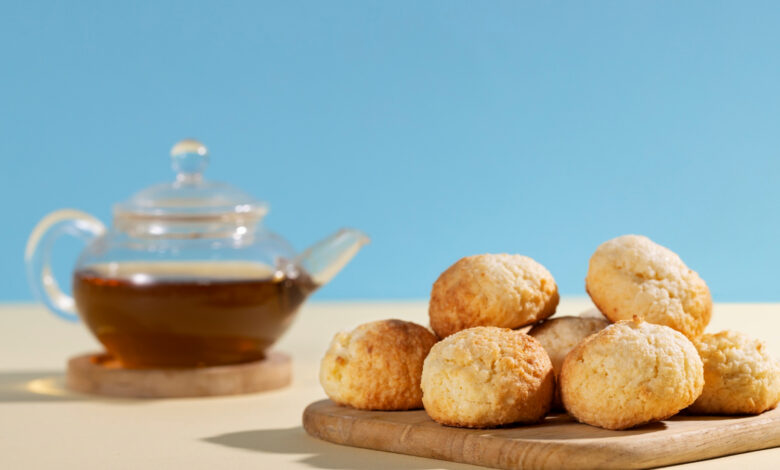 Pãozinhos de tapioca frescos ao lado de uma chaleira de chá, representando a receita fácil e rápida de pãozinho de tapioca.