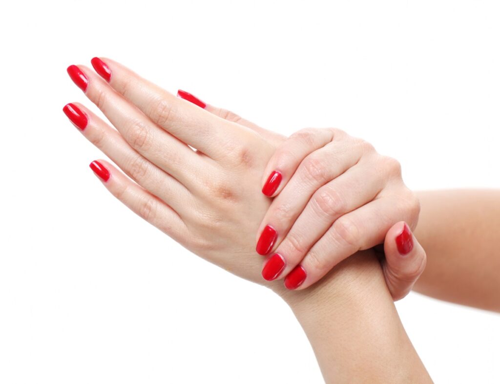 Mãos femininas com unhas pintadas em vermelho vibrante, simbolizando elegância e sofisticação.