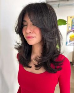 Mulher com o corte de cabelo Kitty Cut, ideal para o verão, com camadas desconectadas e franja.