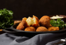 Bolinho de chuva salgado crocante, recheado com purê de batata, servido com folhas de salsa.