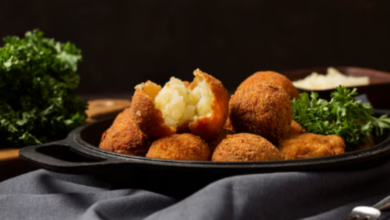 Bolinho de chuva salgado crocante, recheado com purê de batata, servido com folhas de salsa.