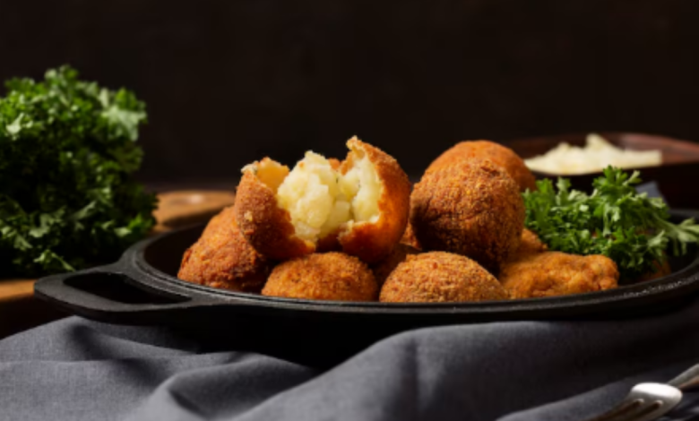 Bolinho de chuva salgado crocante, recheado com purê de batata, servido com folhas de salsa.