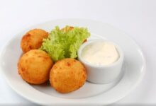 Bolinho de queijo sem trigo servido com molho e alface.