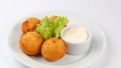 Bolinho de queijo sem trigo servido com molho e alface.