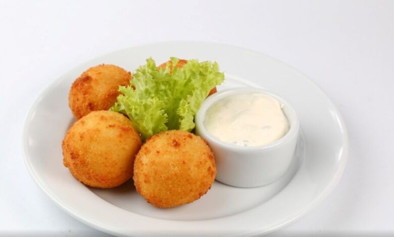 Bolinho de queijo sem trigo servido com molho e alface.