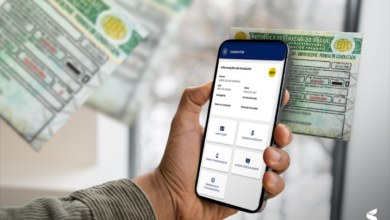 Motorista consulta sua CNH digital pelo celular com versão impressa ao fundo.