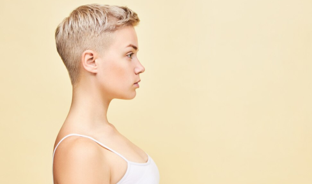 Mulher com corte de cabelo Buzz Cut, estilo curto e minimalista, realçando a praticidade e modernidade do visual.