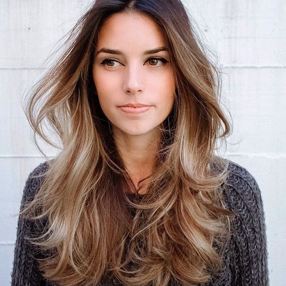 Mulher com cabelo longo e corte em camadas, com fios volumosos e iluminados