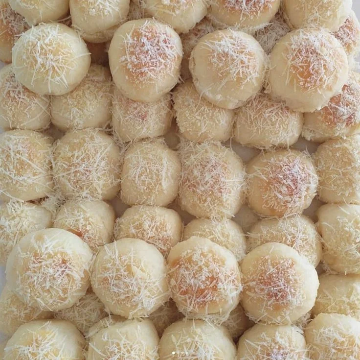 Pãezinhos delícia da Bahia cobertos com queijo ralado, dispostos de forma atraente