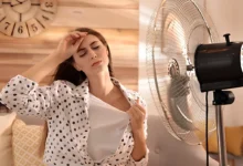 Mulher com calor em ambiente interno, usando ventilador para aliviar o calor extremo