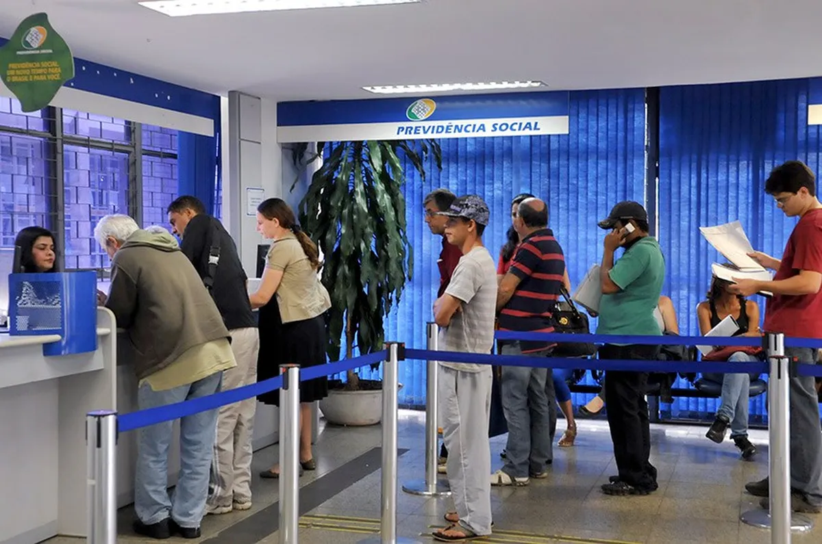 Atendimento no INSS com pessoas na fila aguardando para serem atendidas.