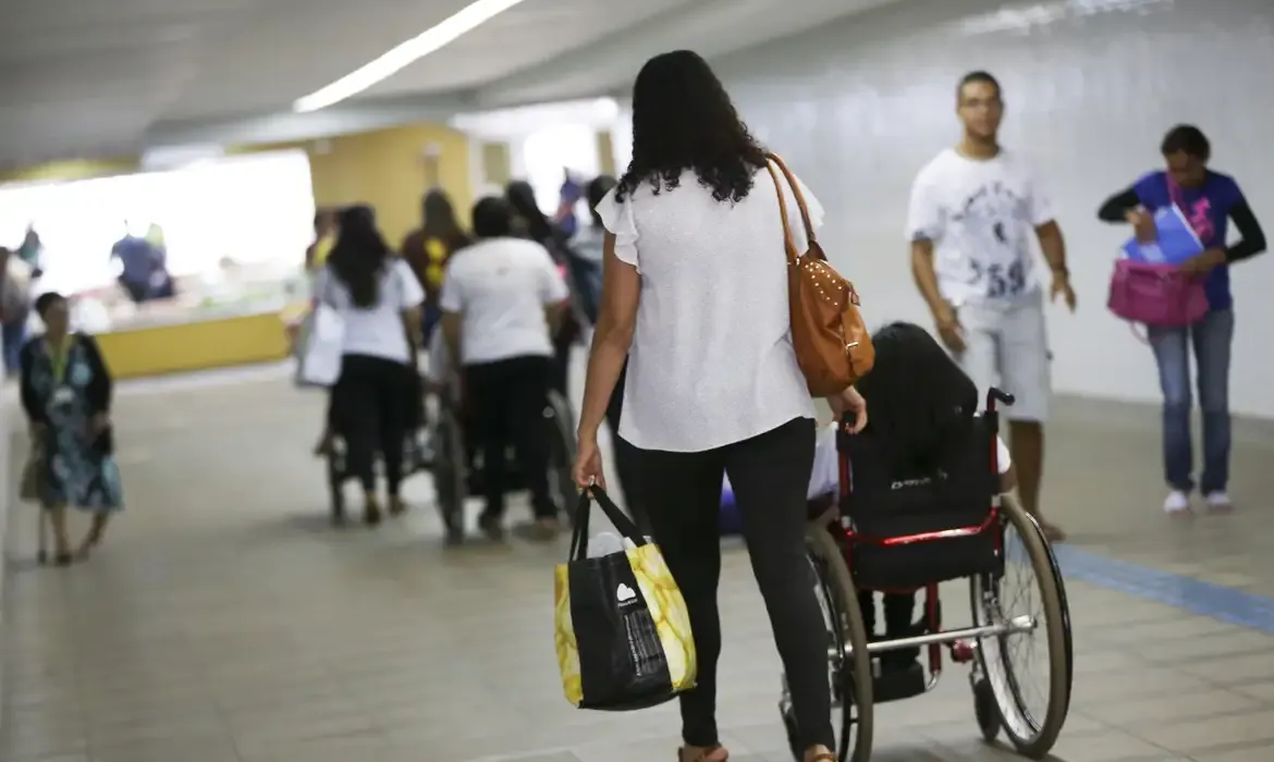 Pessoas em movimento, incluindo uma pessoa em cadeira de rodas, representando beneficiários sendo notificados.