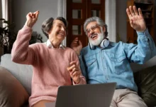 Casal de idosos sorrindo e se divertindo enquanto usa um notebook.