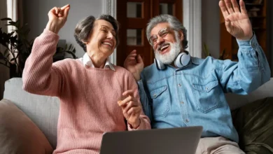 Casal de idosos sorrindo e se divertindo enquanto usa um notebook.