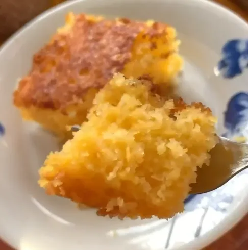 Fatia de bolo de areia fofinho e delicioso, sendo cortada com um garfo.