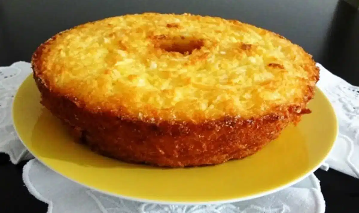 Bolo de mandioca dourado e cremoso servido em um prato amarelo