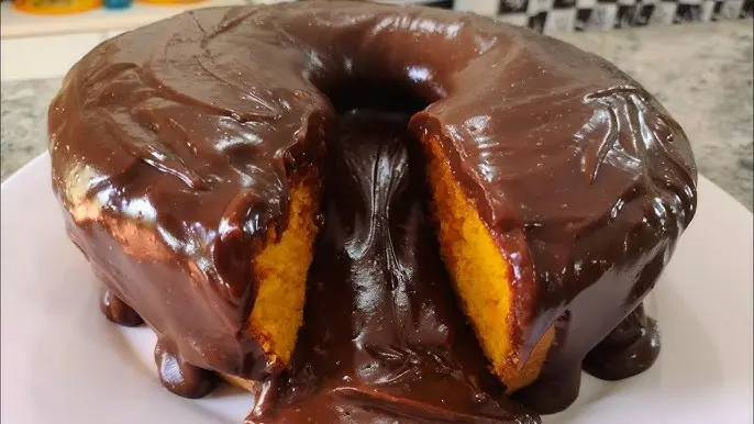 Bolo de cenoura com cobertura de chocolate derretido, servido em prato