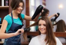 Cabeleireira usando secador e escova para fazer um penteado feminino.