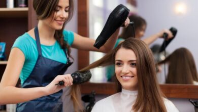 Cabeleireira usando secador e escova para fazer um penteado feminino.