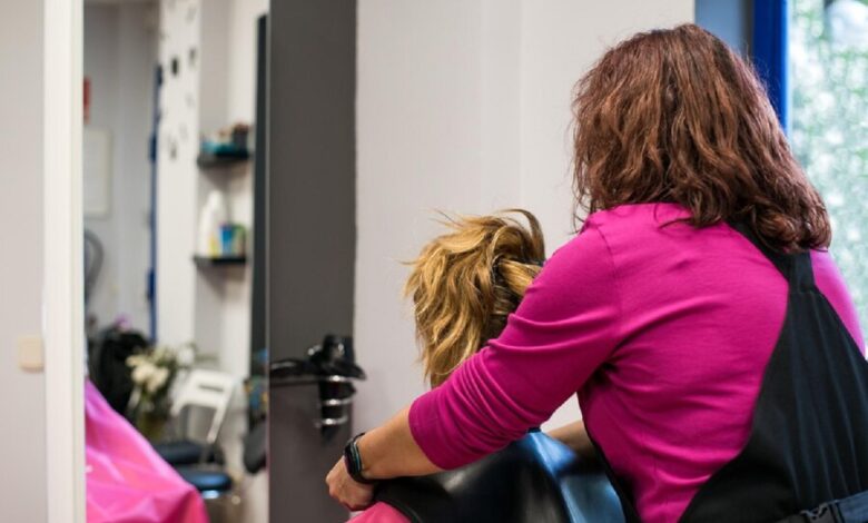 Profissional de cabelo cortando o cabelo de uma cliente em um salão de beleza.