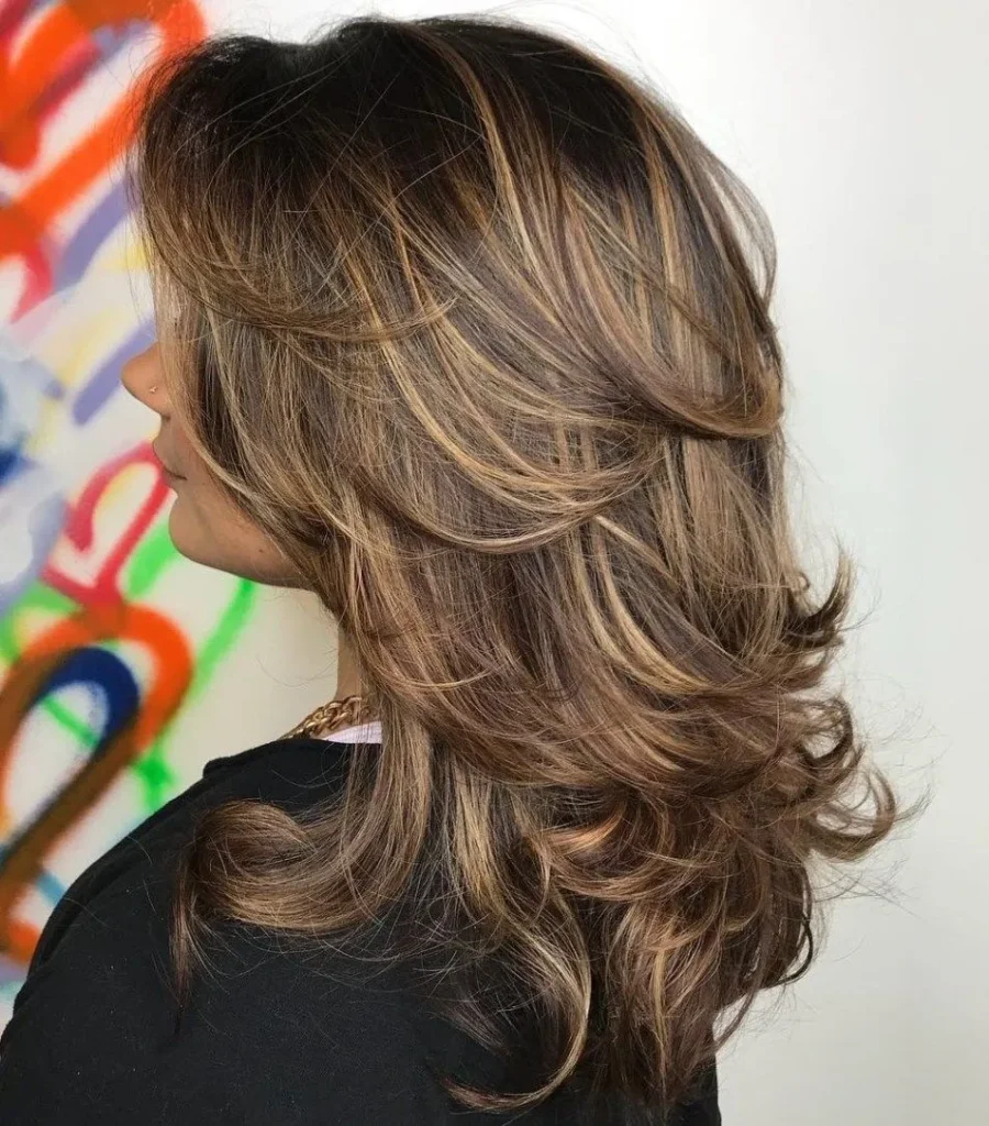 Mulher com cabelo castanho iluminado, com luzes e camadas, exibindo um visual moderno e elegante.