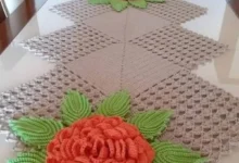 Caminho de mesa em crochê com flores e folhas em alto relevo.