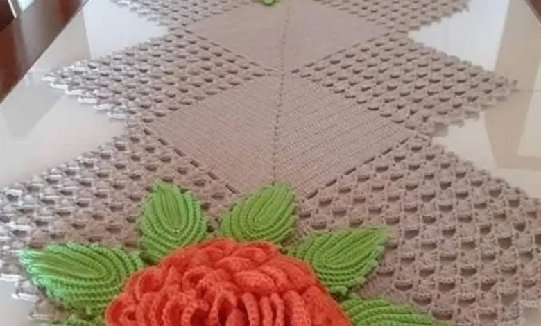 Caminho de mesa em crochê com flores e folhas em alto relevo.