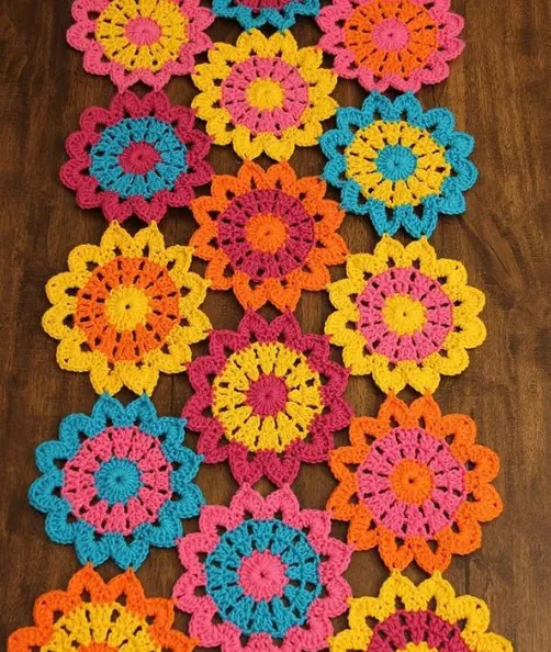 Caminho de mesa de crochê com flores coloridas, mostrando o trabalho artesanal.