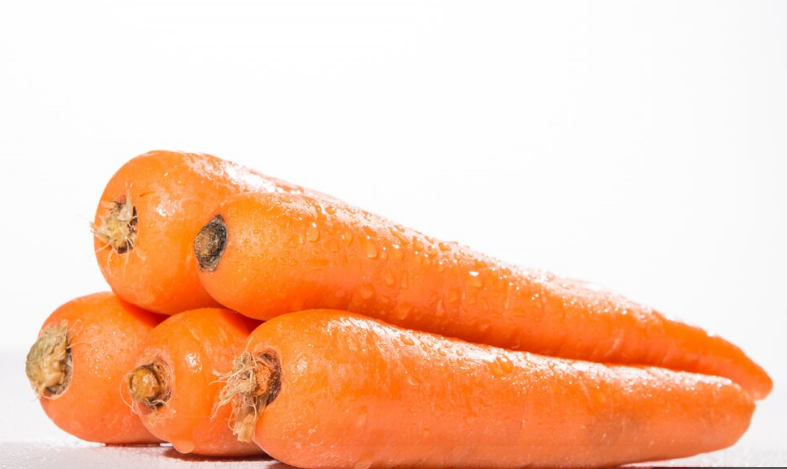 Close-up de cenouras frescas e molhadas, com uma cor vibrante e textura nítida, destacando seu valor nutricional.