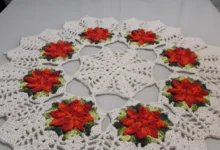 Centro de mesa de crochê com flores coloridas, mostrando um design bonito e elegante em tons de branco, laranja, verde e vermelho.