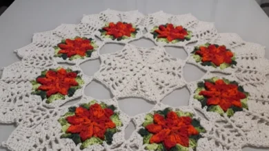 Centro de mesa de crochê com flores coloridas, mostrando um design bonito e elegante em tons de branco, laranja, verde e vermelho.