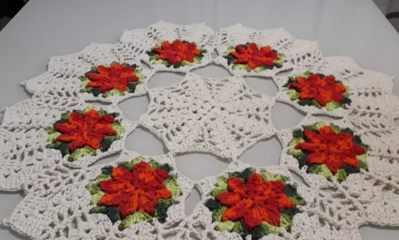 Centro de mesa de crochê com flores coloridas, mostrando um design bonito e elegante em tons de branco, laranja, verde e vermelho.