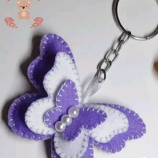 Chaveiro personalizado em forma de borboleta, feito de feltro roxo e branco, com detalhes de pérolas.