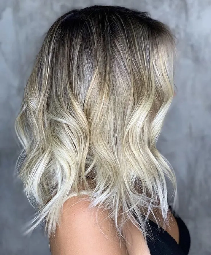 Cabelo long bob loiro com ondas suaves e tonalidade degradê.