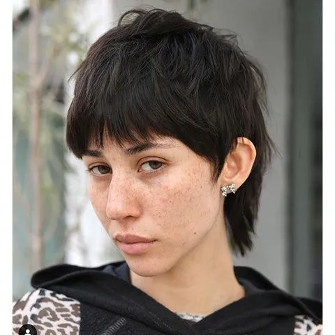 Mulher com corte mullet moderno e franja curta, destacando um estilo ousado e despojado.