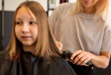 Criança recebendo um corte de cabelo no salão, com o cabelo liso sendo aparado por um profissional.