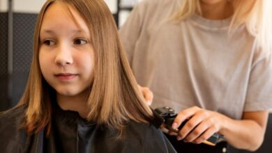 Criança recebendo um corte de cabelo no salão, com o cabelo liso sendo aparado por um profissional.