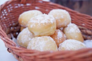 Pãozinhos de leite em pó polvilhados com açúcar, dispostos em uma cesta.