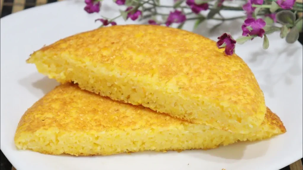 Pão de cuscuz de frigideira dourado e crocante, cortado ao meio, com uma textura macia por dentro