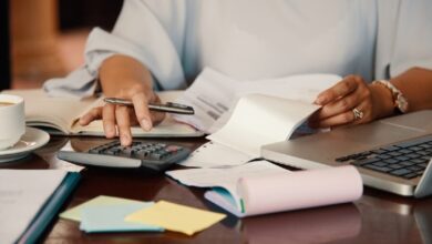 Pessoa revisando documentos e calculando dívidas em uma mesa de escritório, representando o processo de gestão financeira após a morte de um titular.